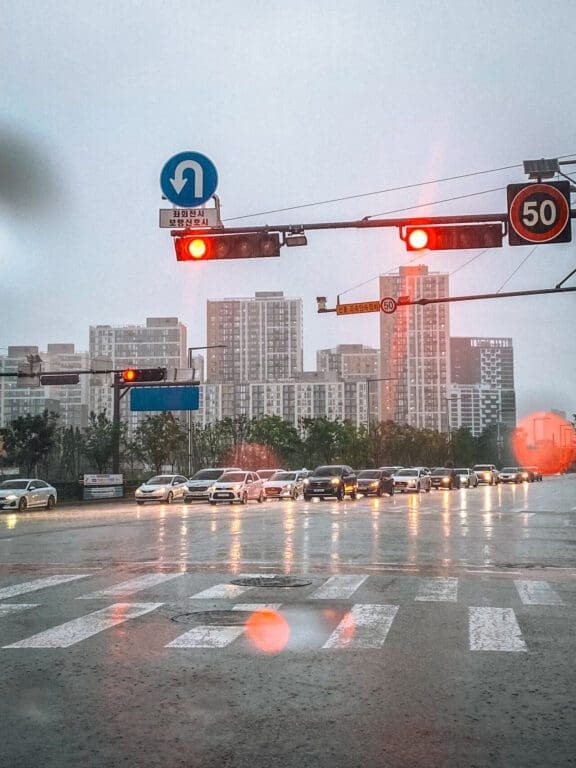 Jjimjilbang 101: Beginner's Guide to Korean Saunas and Bathhouse Etiquette 5 City street traffic during a rainy day in Seoul, illustrating indoor activities like visiting a jjimjilbang.