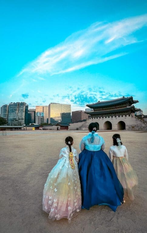 The 5 Royal Palaces in Seoul: A No-Nonsense Expat's Guide to Visiting 1 Three visitors wearing traditional Hanbok walking inside Gyeongbokgung, often considered the best palace in Seoul for photography.