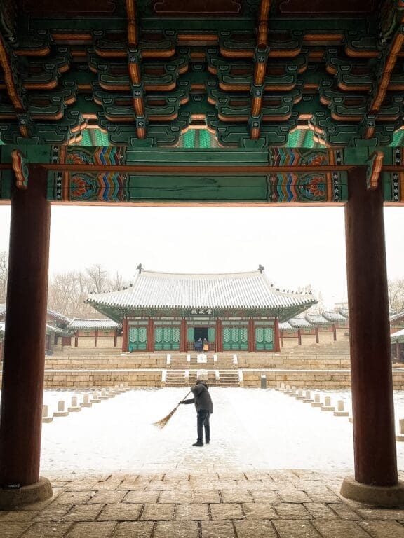 The 5 Royal Palaces in Seoul: A No-Nonsense Expat's Guide to Visiting 13 A caretaker sweeping the stone courtyard in front of Sungjeongjeon Throne Hall at Gyeonghuigung Palace in Seoul.
